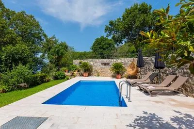 a swimming pool in a garden with two lounge chairs at Villa Brda in Petrovac na Moru