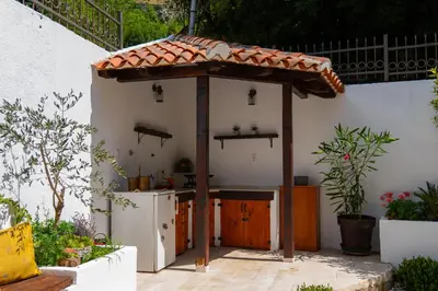 an outdoor kitchen with an umbrella and a refrigerator at Villa Brda in Petrovac na Moru