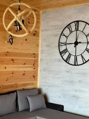 a large clock on a wall next to a couch at Kućica Ušće - Ada Bojana in Ulcinj