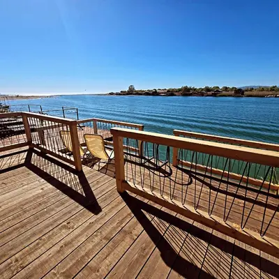 a wooden deck with two benches and the water at Kućica Ušće - Ada Bojana in Ulcinj