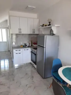 a kitchen with white cabinets and a stainless steel refrigerator at Apartman u zelenilu Bigove in Kotor