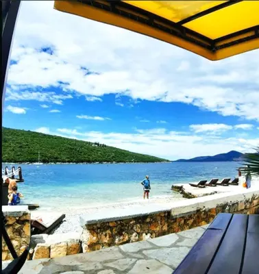a man standing on a beach near the water at Apartman u zelenilu Bigove in Kotor