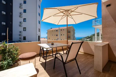 a table and chair with an umbrella on a balcony at Hillside Apartments in Becici