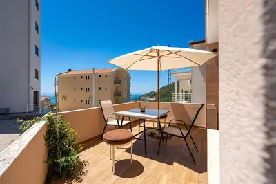 a table and chairs on a balcony with an umbrella at Hillside Apartments in Becici