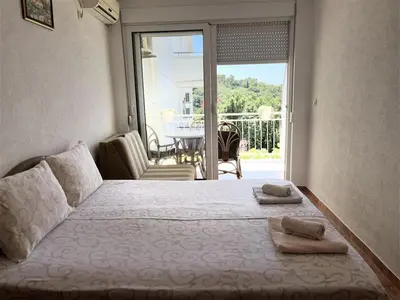 a bedroom with a bed and a balcony with a table at Apartmani Neda Bane in Petrovac na Moru