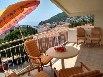 a balcony with chairs and a table and an umbrella at Apartmani Neda Bane in Petrovac na Moru