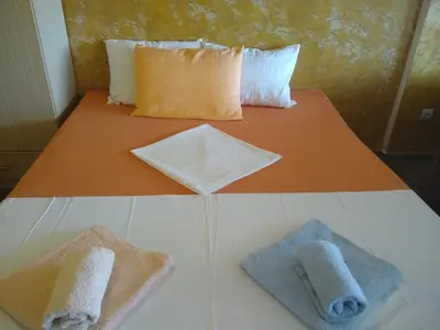 a bed with two towels sitting on top of it at Apartmani Neda Bane in Petrovac na Moru