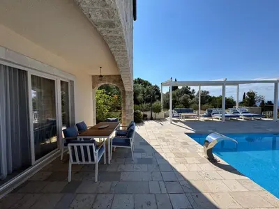 a patio with a table and chairs next to a swimming pool at Casa Oliva Villa with private heating pools in Budva