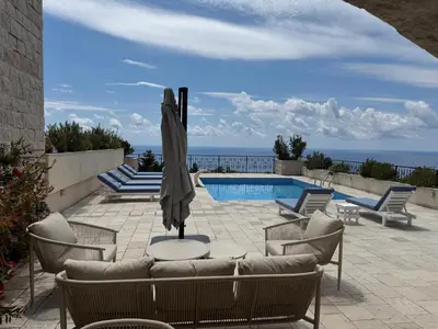 a patio with an umbrella and chairs and a pool at Casa Oliva Villa with private heating pools in Budva