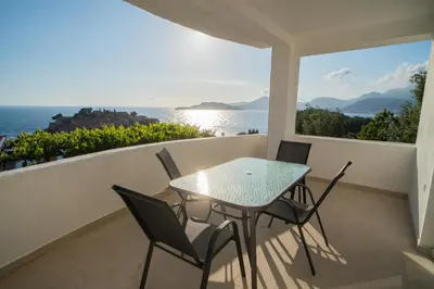 a table and chairs on a balcony with a view of the ocean at Suite Apartment Sveti Stefan in Sveti Stefan