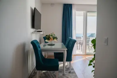 a dining room with a table and chairs and a window at Suite Apartment Sveti Stefan in Sveti Stefan