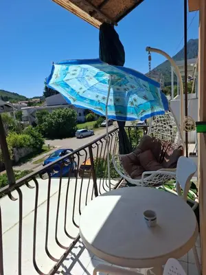 a table and chairs on a balcony with an umbrella at Apartman Ema in Sutomore