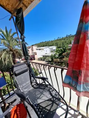 a balcony with a chair and two umbrellas at Apartman Ema in Sutomore