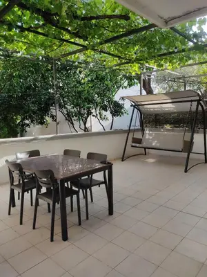 a table and chairs on a patio with a piano at Una apartmani Petrovac in Petrovac na Moru