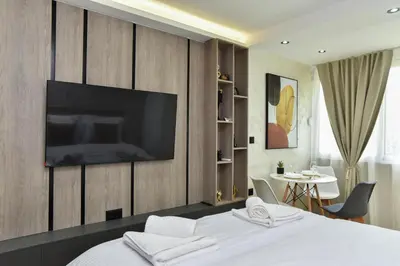 a bedroom with a bed with a television on a wall at ELIT APARTMENTS Budva in Budva