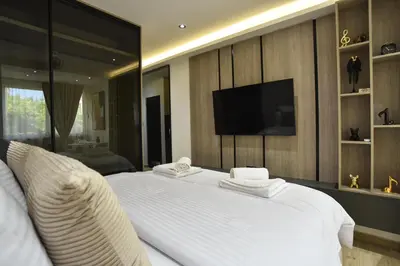 a bedroom with a large white bed with a flat screen tv at ELIT APARTMENTS Budva in Budva