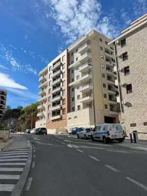 a street with cars parked in front of a building at Anja Apartment in Becici