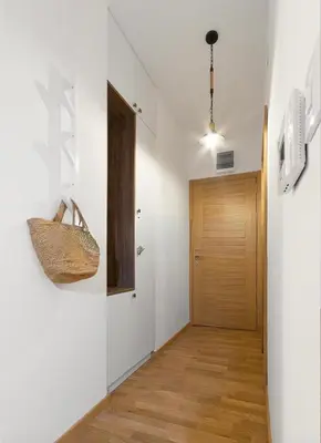 a hallway with white walls and a wooden door at Anja Apartment in Becici