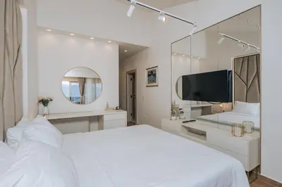 a white bedroom with a large bed and a tv at Villa Principium with Infinity Edge Pool&Hot Tub in Kotor