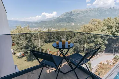 a table and two chairs on a balcony with a view at Villa Principium with Infinity Edge Pool&Hot Tub in Kotor