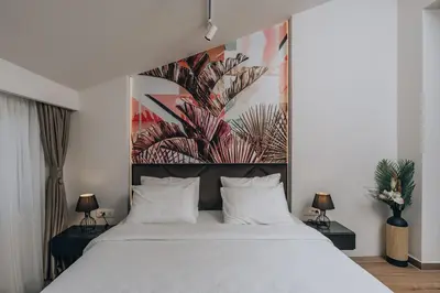 a bedroom with a white bed with a large painting on the wall at Villa Principium with Infinity Edge Pool&Hot Tub in Kotor