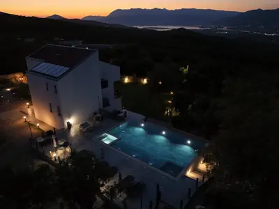 a villa with a swimming pool at night at Villa Principium with Infinity Edge Pool&Hot Tub in Kotor