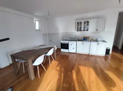 a kitchen with a wooden table and white cabinets at Fun and spacious apartment in Budva