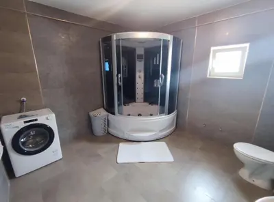 a bathroom with a washing machine and a toilet at Fun and spacious apartment in Budva
