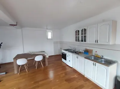 a kitchen with white cabinets and a table and chairs at Fun and spacious apartment in Budva
