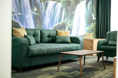 a green couch in a living room with a waterfall mural at M&N Holiday Resort in Ulcinj
