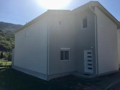 a white house with the sun on top of it at Family house VND in Kotor