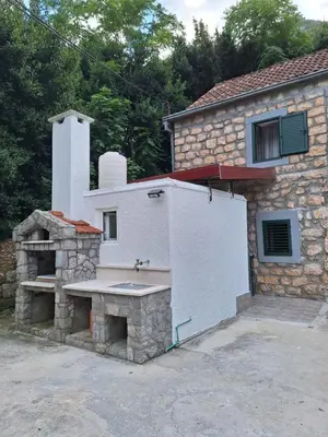 a stone building with a stone fireplace next to a house at Old stone house Danka in Kotor
