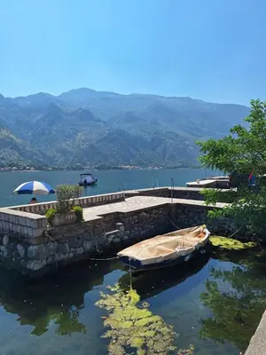 a boat in the water next to a stone wall at Old stone house Danka in Kotor