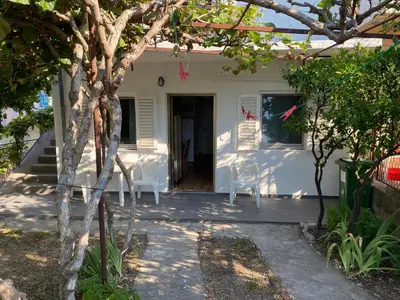 a white house with two chairs and a tree at Deskos Cottage in Sutomore in Zgrada