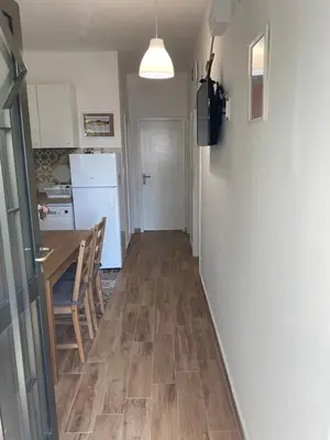 a hallway of a kitchen with a table and a refrigerator at Deskos Cottage in Sutomore in Zgrada
