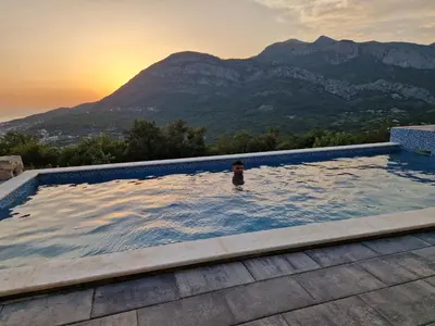 a person in a swimming pool with mountains in the background at Villa Monza in Bar