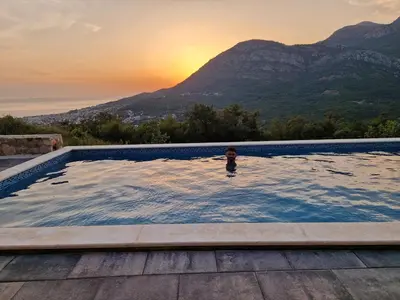 a person in a swimming pool with a mountain in the background at Villa Monza in Bar