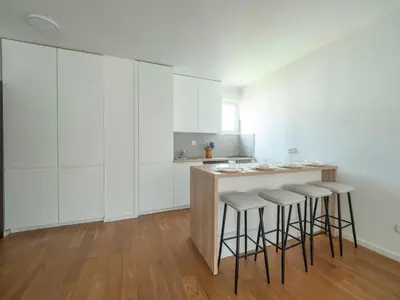 a kitchen with white cabinets and bar stools at Classy Two-Bedroom Apartment in Budva