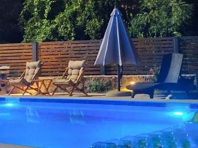 two chairs and an umbrella next to a swimming pool at Villa Bartula Lux in Rap
