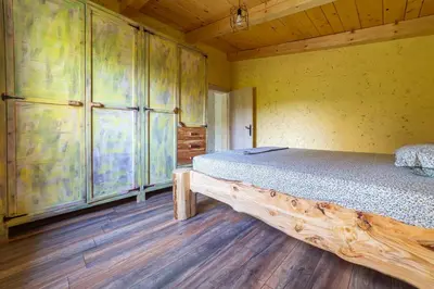 a bedroom with a bed in a room with wooden floors at Rustic Cottage Montenegro Bridje in Podgorica