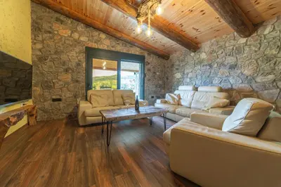 a living room with couches and a stone wall at Rustic Cottage Montenegro Bridje in Podgorica