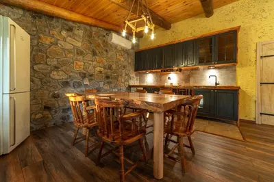 a kitchen with a wooden table and wooden chairs at Rustic Cottage Montenegro Bridje in Podgorica
