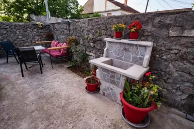 a stone wall with a sink and potted plants at Apartmani Kaan in Podgorica