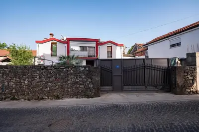 a house with a black gate and a stone wall at Apartmani Kaan in Podgorica