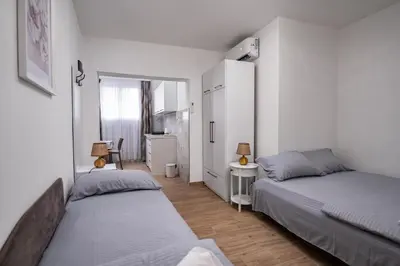 two beds in a room with white walls and wooden floors at Apartmani Kaan in Podgorica