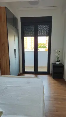 a bedroom with a bed and sliding glass doors at Podgorica apartments Planet in Podgorica