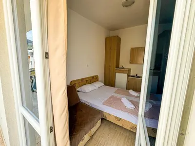 a small bedroom with a bed in the middle at Biser Apartmani in Dobra Voda