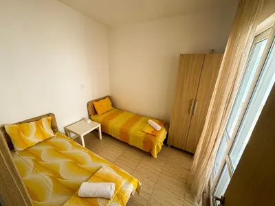 a small bedroom with two beds and a window at Biser Apartmani in Dobra Voda