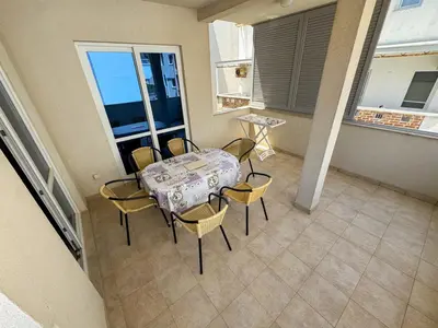 a dining room with a table and chairs on a balcony at Biser Apartmani in Dobra Voda
