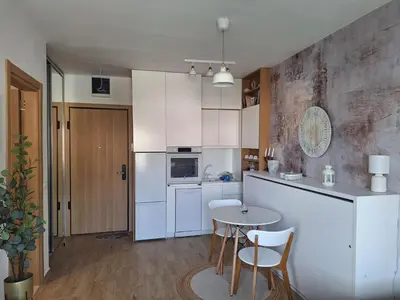 a kitchen with white cabinets and a table and chairs at Kupidon in Dobra Voda